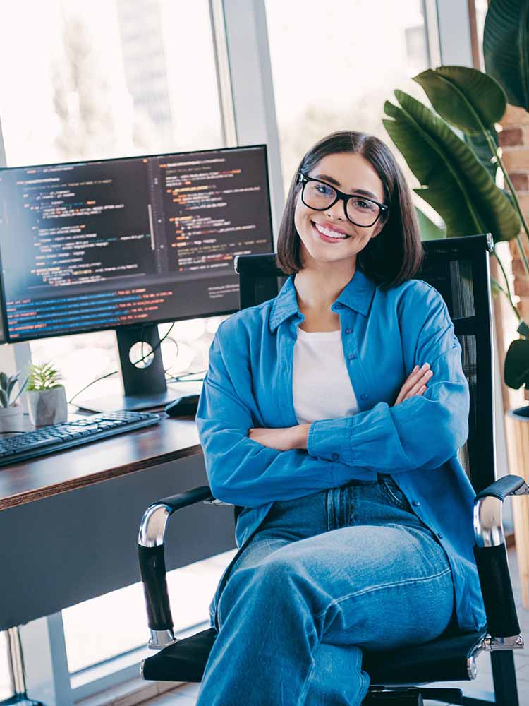 Female coder smiling at desk.