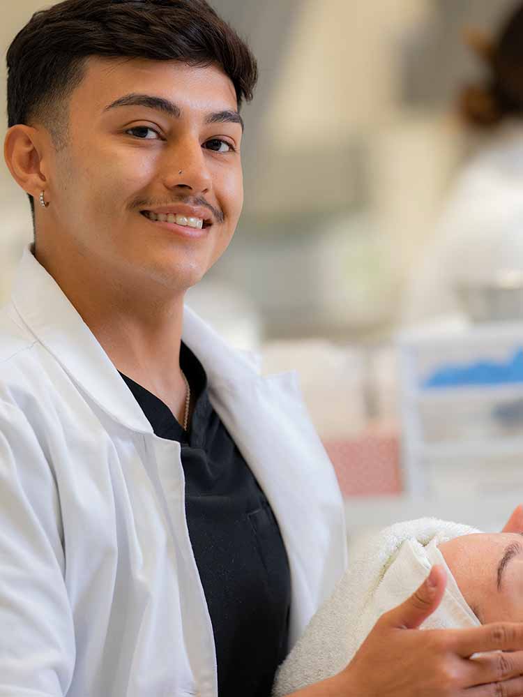 male cosmetology student giving client a facial