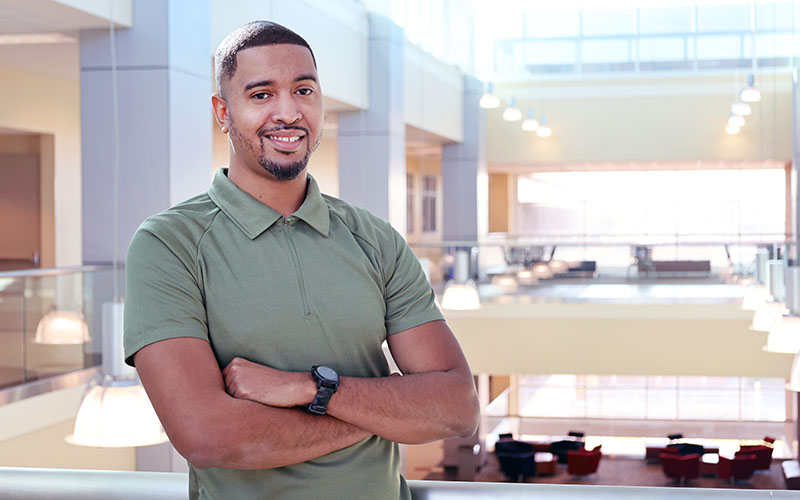 STEM student Lorenzo Lewis standing with arms crossed in science building atrium